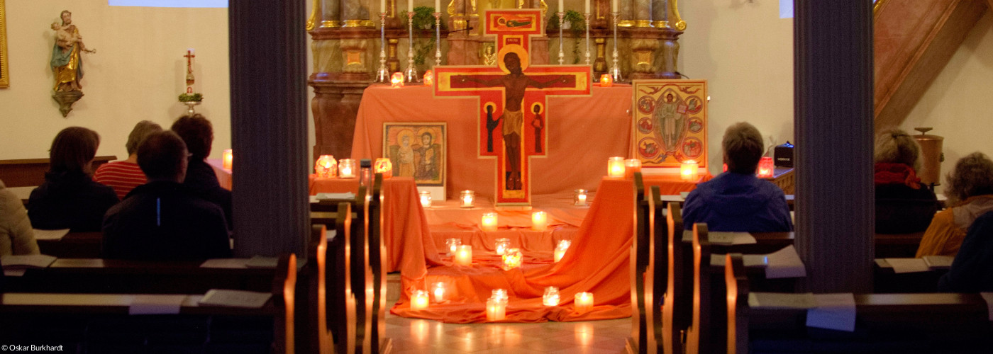 viele Kerzen brennen am Altar vor dem Taizékreuz und den Ikonen