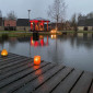 Eisweiher mit Kerzen am Steg und erleuchtetem Pavillon (Weihnachten 2023)