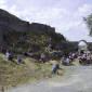 Gottesdienstbesuchende sitzen vor der Burgmauer und auf den Stühlen zwischen Burgmauer und der Scheune
