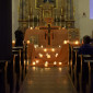 viele Kerzen brennen am Altar vor dem Taizékreuz und den Ikonen