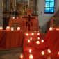 Blick von vorne auf den Taizé-Altar mit vielen brennenden Kerzen vor dem Taizékreuz