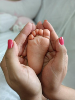 Babyfuß wird gehalten von 2 Frauenhänden