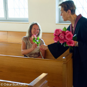 Prädikantin Gertraud Burkhardt überreicht einer Gottesdienstbesucherin eine Rose